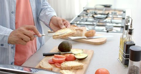 Man spreads butter on bread for wholesome breakfast in modern kitchen