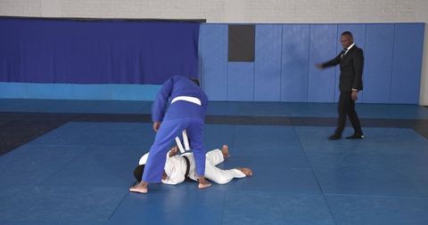 Martial artists sparring with referee in gym training session