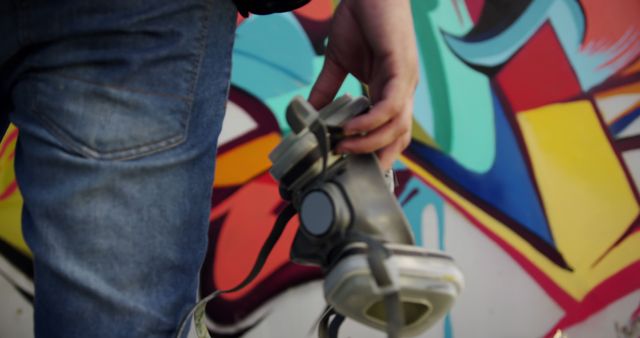 Urban Street Artist Holding Respirator Mask with Colorful Graffiti Wall - Download Free Stock Images Pikwizard.com