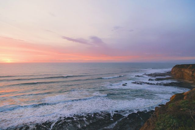 Capturing the serene beauty of the ocean meeting the shore at sunset, this image showcases breathtaking colors in the sky with gentle waves below. Perfect for use in travel brochures, nature websites, or as aesthetic wall art to evoke calm and wonder.