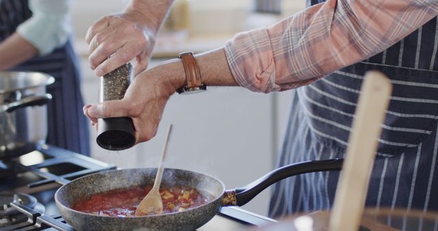 Man seasoning sauce in kitchen with pepper grinder - Download Free Stock Images Pikwizard.com