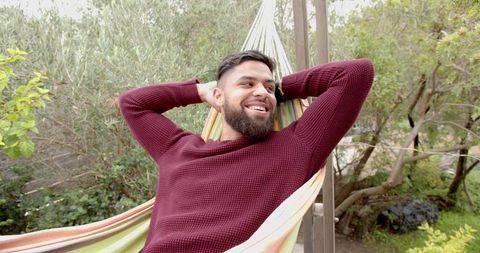 man relaxing on striped hammock in lush garden setting - Download Free Stock Images Pikwizard.com