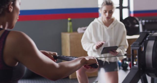 Women Training on Rowing Machine with Female Coach in Gym - Download Free Stock Images Pikwizard.com