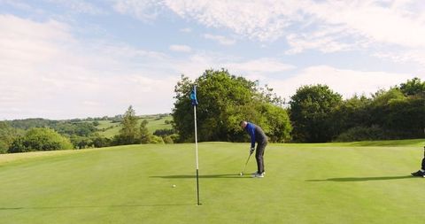 Golfer putting on green with caddie: sports and leisure scene