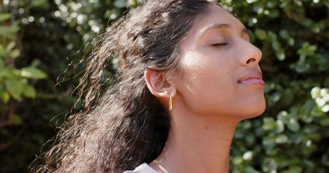 Sunlit serenity portrait of african american woman standing with eyes closed and gold jewelry