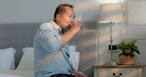 Senior Man Drinking Water in Cozy Bedroom for Relaxation and Hydration