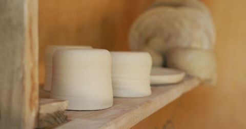 Handmade clay pottery pieces on workshop shelf