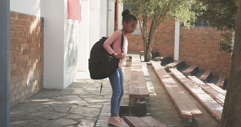 Young Schoolgirl with Backpack on Courtyard Benches