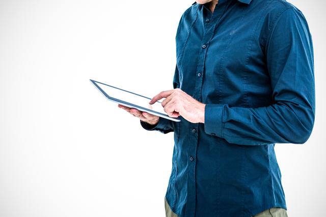Professional businessman in blue shirt holding and using tablet with white background. Ideal for business, technology-related promotions, modern work scenarios, or digital interfaces demonstrations.