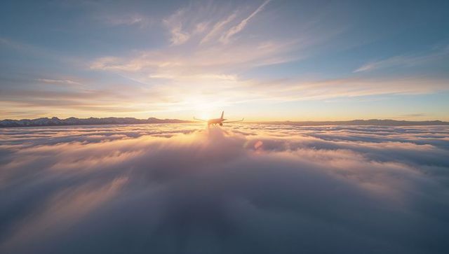Jet Plane Gliding Between Cloud Layers During Sunrise Glory