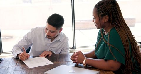 Business professionals signing agreement in modern office