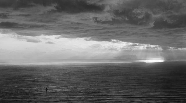 Solitary Fisherman Under Overcast Skies at Sea - Download Free Stock Photos Pikwizard.com