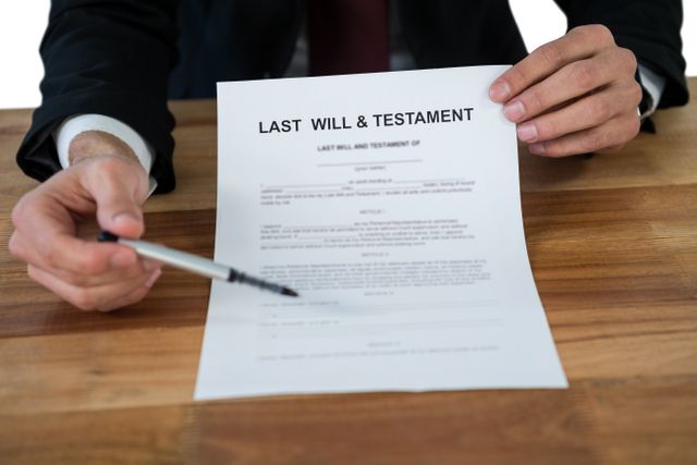 Businessman holding and pointing to a last will and testament form. Ideal for use in articles or advertisements related to legal services, estate planning, inheritance, and law firms. Can also be used in educational materials about the importance of having a will.