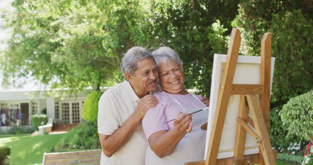 Image of happy biracial senior couple painting in garden. active retirement lifestyle, senior relationship, hobby and spending time together.