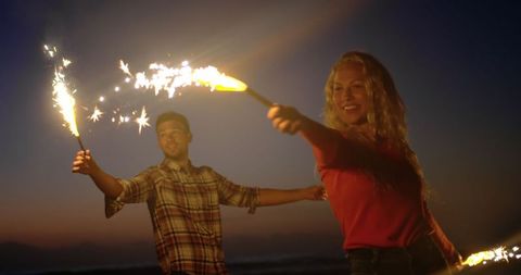 Happy Couple Enjoying Sparklers on a Beach at Dusk