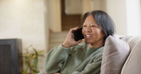 Senior asian woman enjoys comfortable phone conversation at home