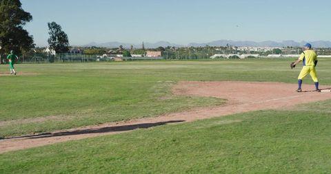 Suburban Baseball Players Standing on Infield Dirt Near First Base with Mountain Backdrop