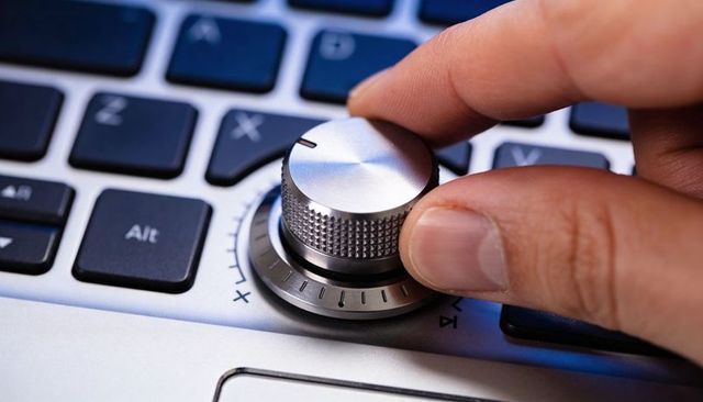 Right hand rotating metallic rotary knob on laptop keyboard closeup for precision control