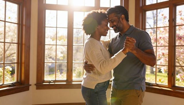 Sunlit couple dancing embracing near bay window cozy romantic home moment spring backlit
