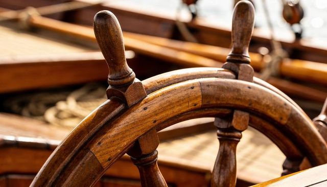 Varnished wooden ship wheel close-up showcasing vintage nautical helm and timber grain