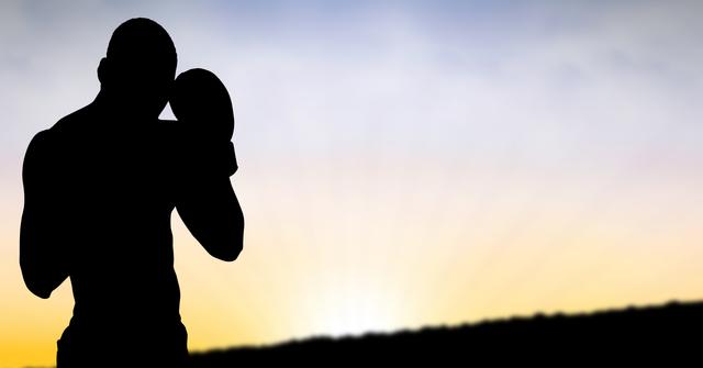 Silhouette of a man wearing boxing gloves, training during sunset. Ideal for use in fitness and sports promotions, motivational posters, and outdoor exercise campaigns. The image conveys themes of strength, determination, and perseverance.