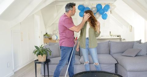 Mature Couple Joyfully Cleaning Party Decorated Living Room