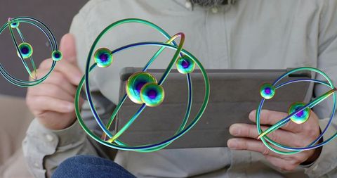 Holding tablet, mature man interacting with iridescent orbital holograms on sofa
