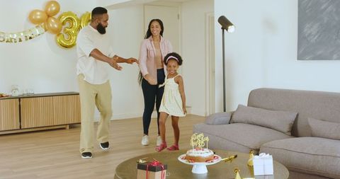 Family celebrating birthday with homemade cake at home