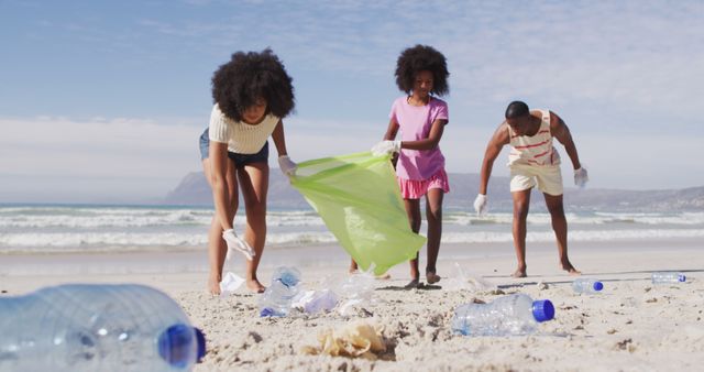 African american parents with their children collecting rubbish and bottles from the beach. family eco beach conservation.