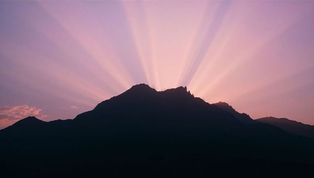 Dawn Mountain Silhouette with Radiating Sunbeams