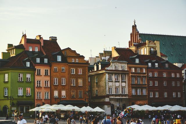 Features colorful historical buildings in Warsaw's Old Town Square. Perfect for illustrating European travel, urban exploration, historical architecture, and city tourism. It captures the charm and cultural heritage typical of Warsaw, making it suitable for travel guides, cultural presentations, and promotional materials for tourism.