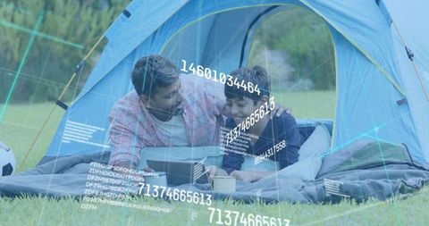 Father and son camping using tablet with augmented reality data overlays