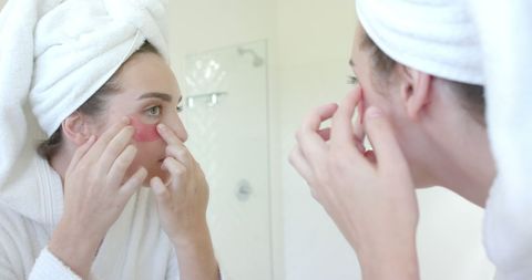Woman Applying Skincare Patches in Bathroom for Healthy Glowing Skin