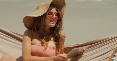Cheerful Woman Relaxing with Tablet on Sunny Beach