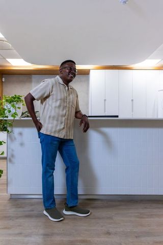 Man leaning on white tiled counter in modern minimalist kitchenette reception smiling casually