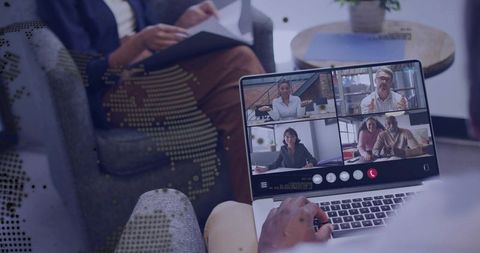 Hybrid team joining virtual meeting on laptop in casual lounge workspace with global map overlay