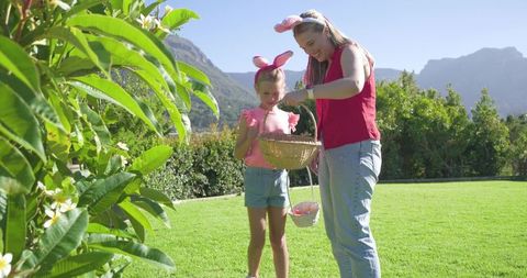 African american mother daughter wearing bunny ears easter egg hunt sunny backyard