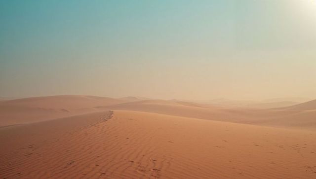 Sweeping Sand Dunes Under Vast Blue Sky in Desert Landscape