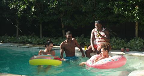 Group of friends relaxing on inflatable pool floats in backyard