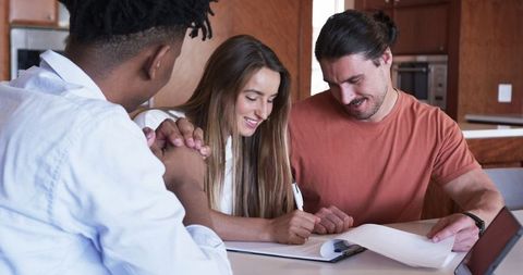Friends discussing plans and smiling at home over documents