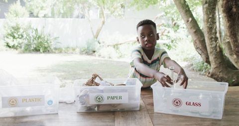 Young boy sorting recycling outdoors encourages environmental education