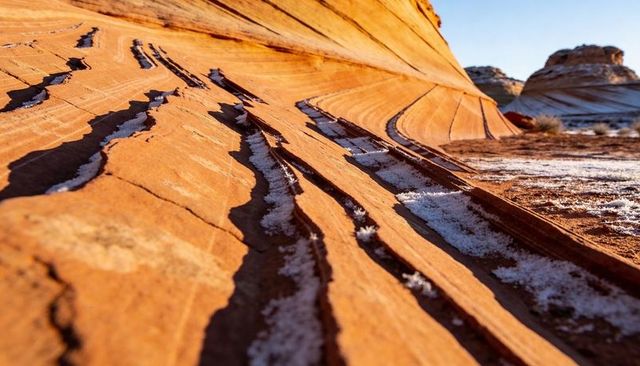 Frosted sandstone ridges curving over sunlit desert striations and domes
