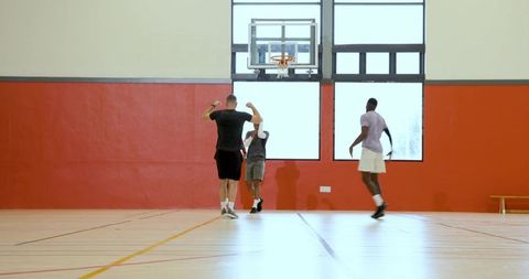 Casual indoor pickup basketball game with three teammates celebrating under hoop