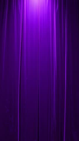 Vertical video turning on spotlight, casting purple wash on theater curtain, readying stage