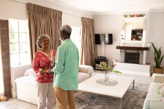 A senior African American couple at home together, social distancing and self isolation in quarantine lockdown during coronavirus covid 19 epidemic, standing looking at each other holding hands.