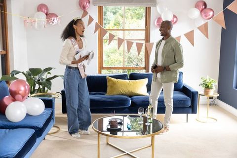 Surprised birthday woman receiving gift from partner in festive modern living room