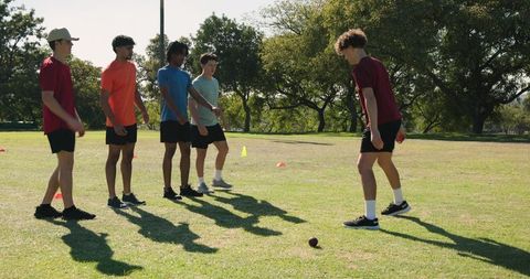 Indian coach leading diverse male athletes through outdoor agility drills and stretching