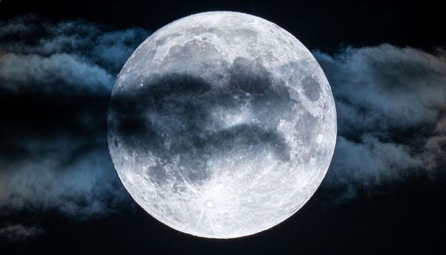 Luminous Full Moon with Crater Detail and Veiled Cloud Bands in Dark Night Sky