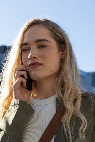 Young woman talking on smartphone while walking city street, urban lifestyle portrait