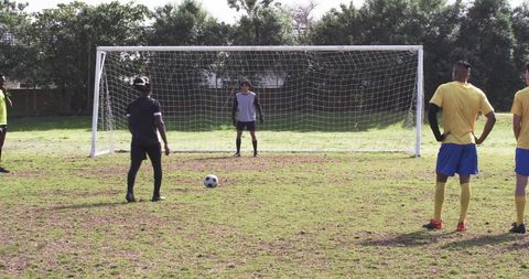 Soccer team practicing penalty kicks in park
